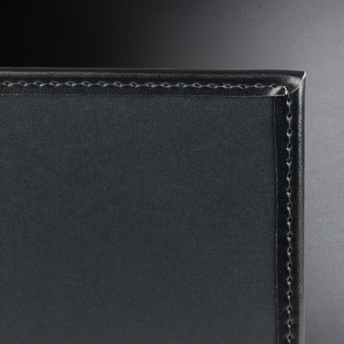 Close-up of a black leather product with visible stitching on a dark background