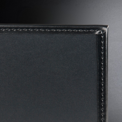 Close-up of a black leather product with visible stitching on a dark background