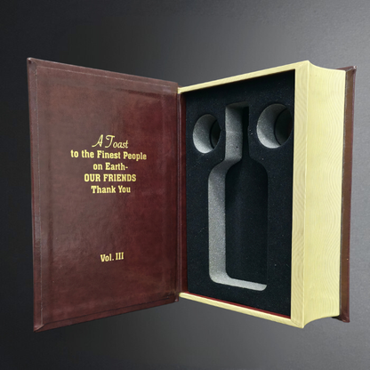 Decorative book with engraved text and two silver objects inside on a dark background