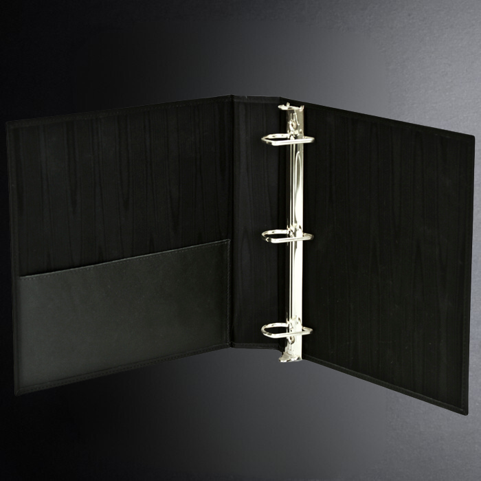 Black leather-bound book with a silver metal clip on a dark background