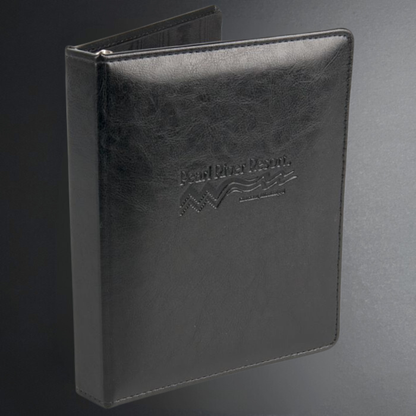 Black leather-bound book with embossed logo on a gray background