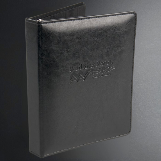 Black leather-bound book with embossed logo on a gray background