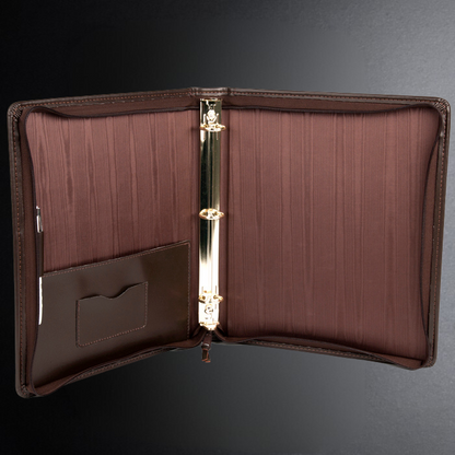 Brown leather portfolio with gold clip on a dark background