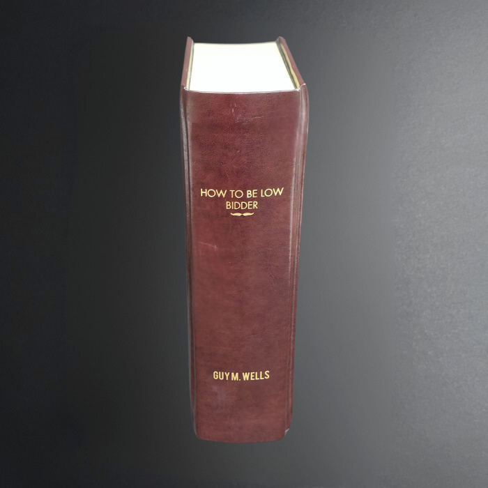 Book titled 'How to Be a Low Bidder' by Guy M. Wells on a dark background