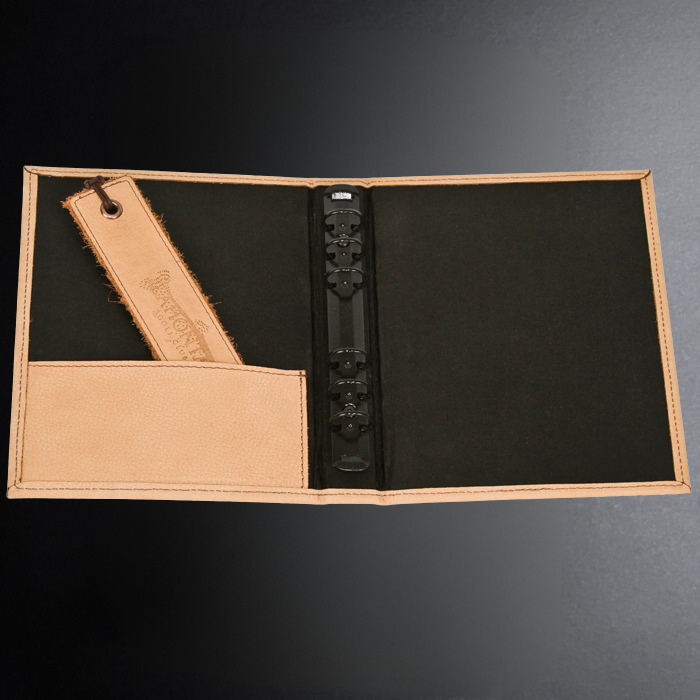 Open leather-bound book with black interior pages on a dark background