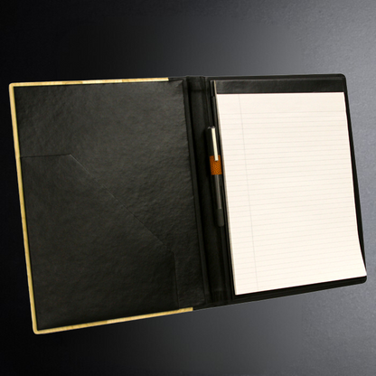 Black leather portfolio with a pen holder and lined paper on a dark background