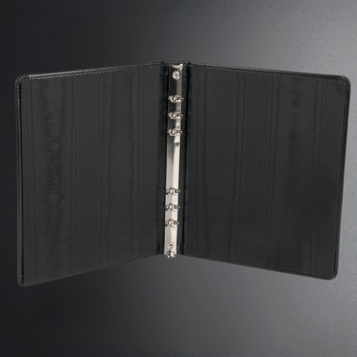 Black leather notebook with metal rings on a dark gray background