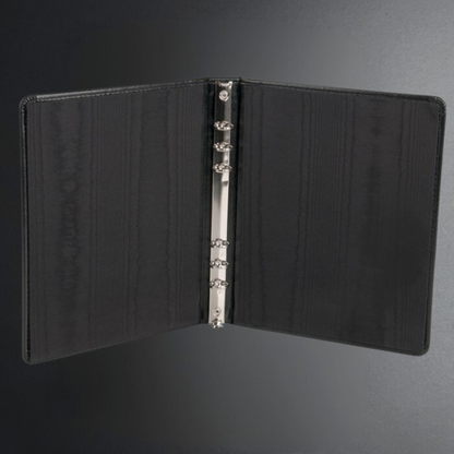 Black leather notebook with metal rings on a dark gray background