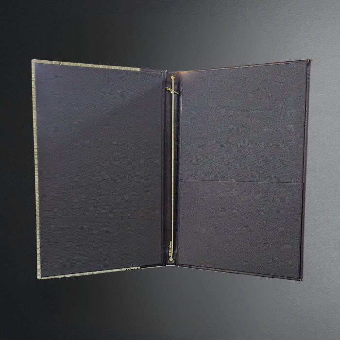 An open black binder or folder with a textured fabric cover, gold-toned metal rings, and a dark gray background.