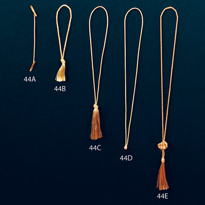 Set of five gold tassels labeled 44A to 44E on a dark green background