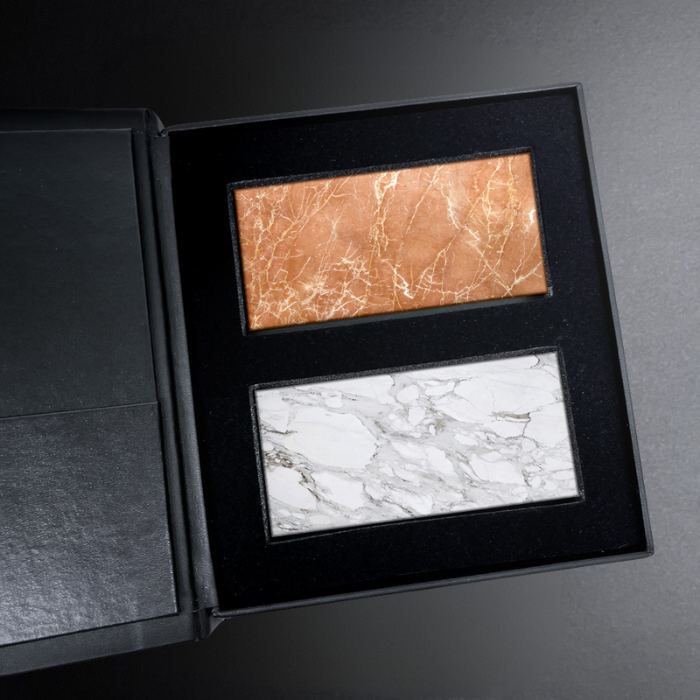 Two marble-patterned tiles in a black display box on a gray surface.
