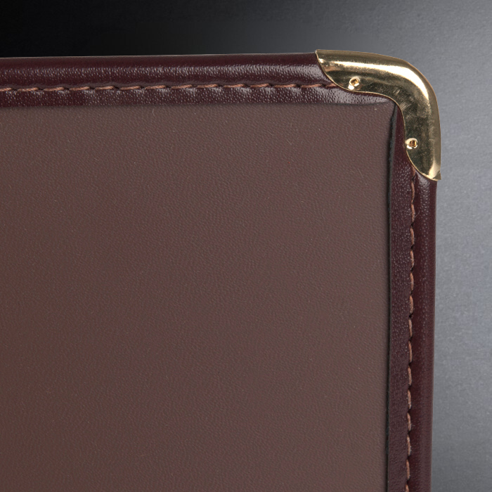Brown leather wallet corner with gold stitching on a dark background