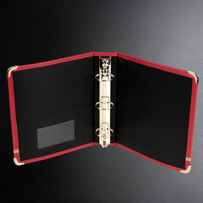 Red-bound binder with black interior on a dark background