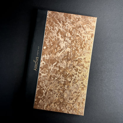 A menu cover with a copper kettle majilite finish and black foil debossing, featuring a textured embossed pattern.