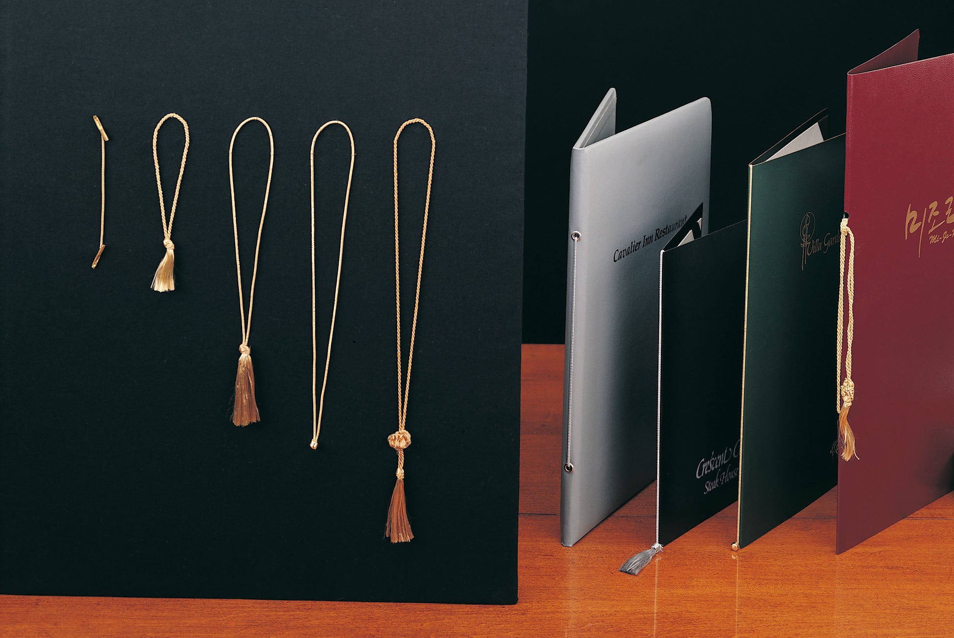 Gold tassel necklaces on a black background with books in the foreground.