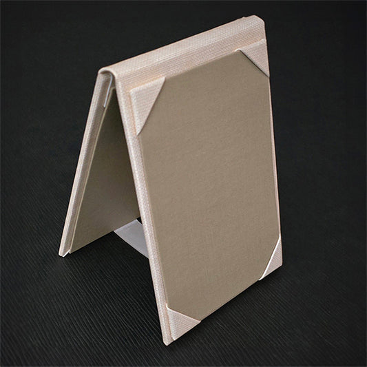 A beige table tent with a book cloth lining, constructed from faux leather and set on a dark background.