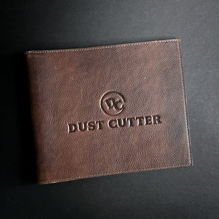 A closed dust cutter with 'DUST CUTTER' embossed on the cover, constructed from brown genuine leather.