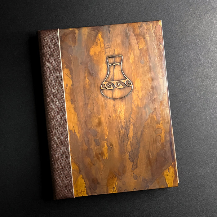Antique copper pocket menu cover with die cut inserts and a embossed logo on the front.