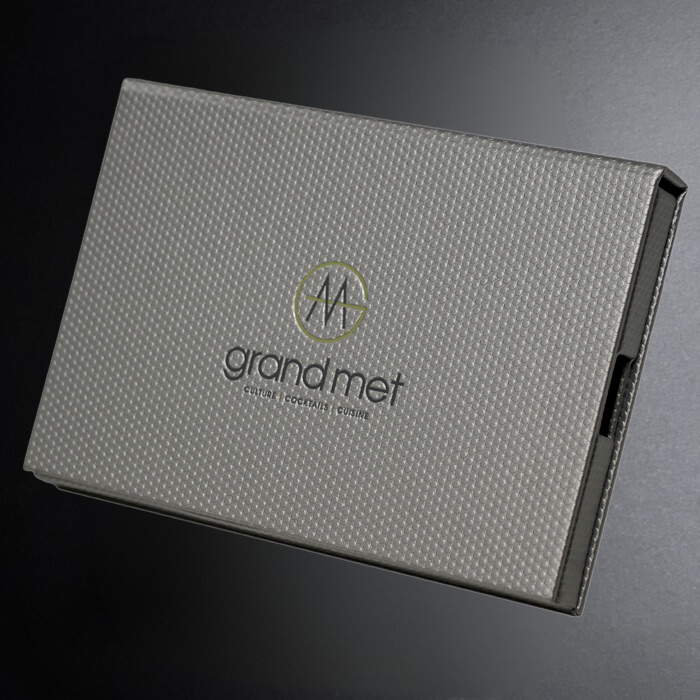 Gray textured box with 'grand met' branding on a dark background