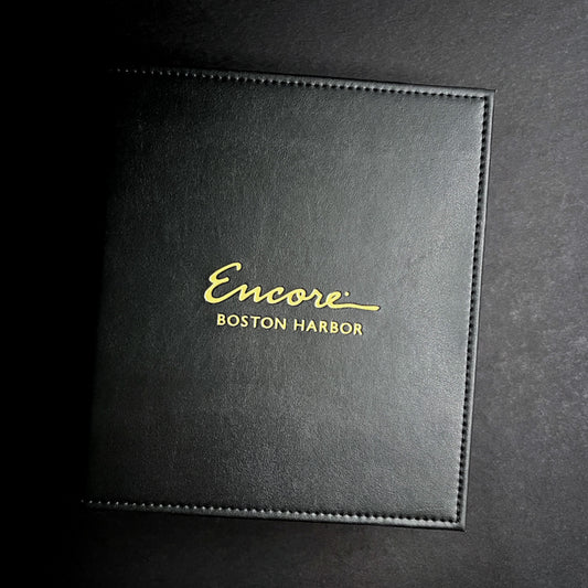 A black three-ring binder with the logo 'Encore Boston Harbor' debossed in gold on the front cover.