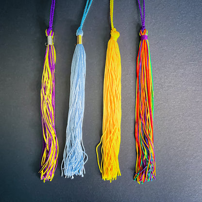 Four colorful tassels on a dark gray background