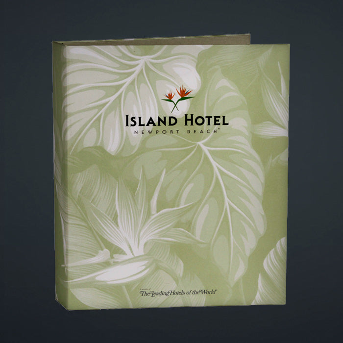 A directory binder with a green cover featuring a printed litho design with palm leaves and the text 'Island Hotel - Newport Beach'. It has a turned edge construction and a linen book cloth liner.