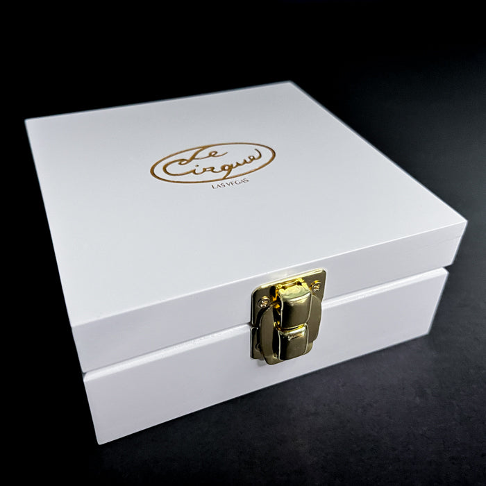 A white lacquer wood box with a gold clasp closure, engraved with the logo 'Le Cirque' on the lid.