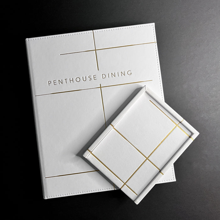 A white Vienna tray with gold felt bottom and gold foil debossing on the cover, labeled 'Penthouse Dining'.