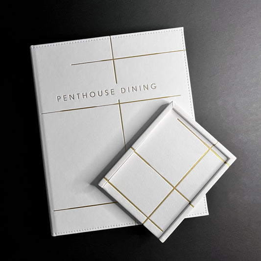 A white Vienna tray with gold felt bottom and gold foil debossing on the cover, labeled 'Penthouse Dining'.