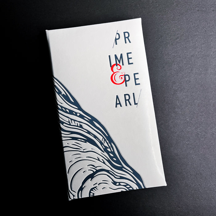 A closed white guest check with 'PRIME & PEARL' text and a decorative design in blue and gray on the cover.