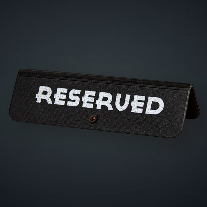 A black leather reserved sign with white text 'RESERVED' and a decorative element at the back.