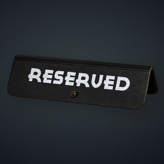 A black leather reserved sign with white text 'RESERVED' and a decorative element at the back.