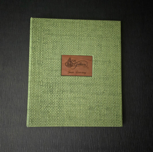 A green guest directory with a brown engraved wood tip on the cover, featuring a basketweave pattern and a 6-ring binder mechanism.