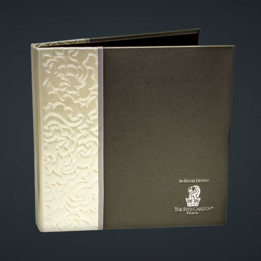 A directory binder with a steel vienna cover featuring a blind deboss pattern on the spine and a foil deboss logo of The Ritz-Carlton, Phoenix. The binder is constructed with a turned edge and has a patent faux leather cover.