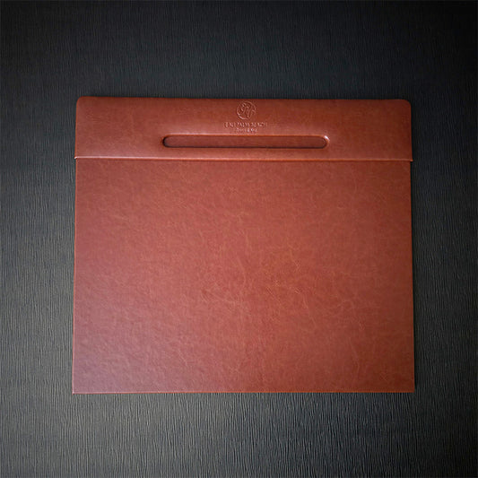 A rectangular desk blotter with Italian faux leather cover in brown, featuring a debossed logo on the top edge.