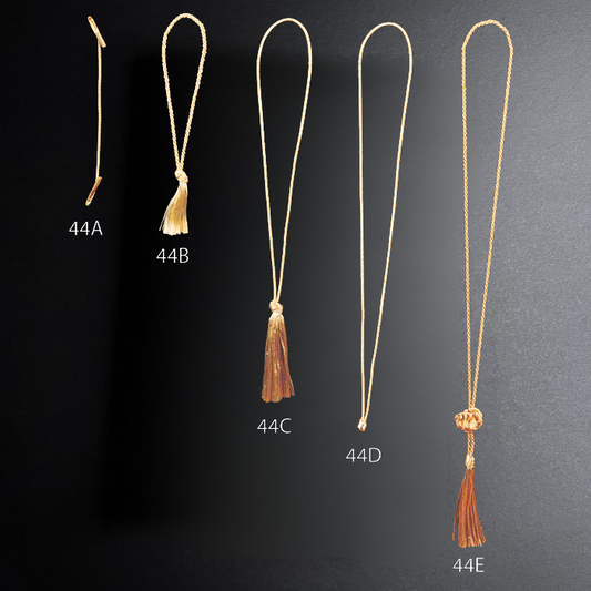 Set of five gold necklaces with brown tassels on a dark background