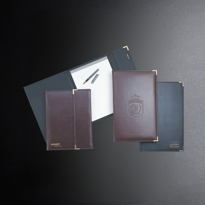 Collection of leather-bound notebooks with embossed logos on a dark background
