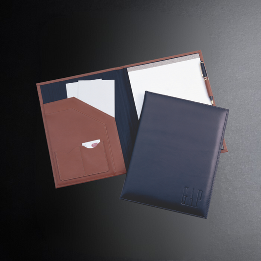 Two leather-bound notebooks with a pen on a dark surface