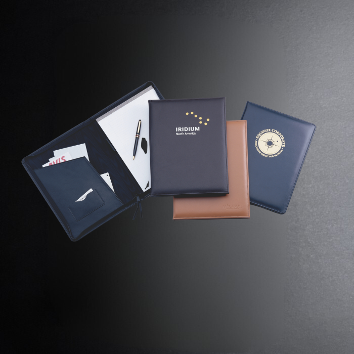 Collection of leather-bound notebooks with visible branding on a dark surface