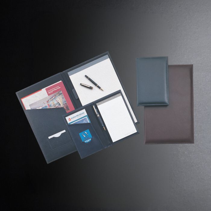 Collection of office supplies including notebooks, a pen, and cards on a dark surface