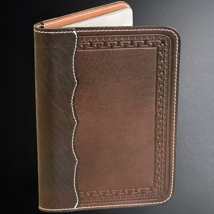 Brown leather notebook with intricate stitching on a dark background