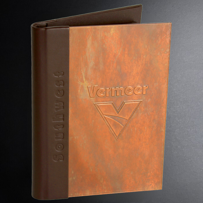 Brown and orange embossed notebook with 'Vermeer' branding on a dark background