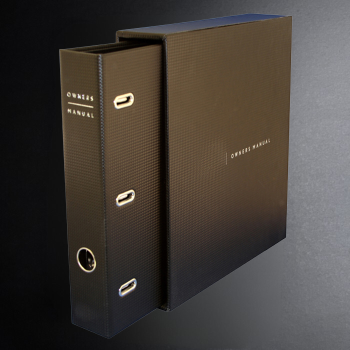 Brown ring-bound manual with 'Owners Manual' text on a gradient background