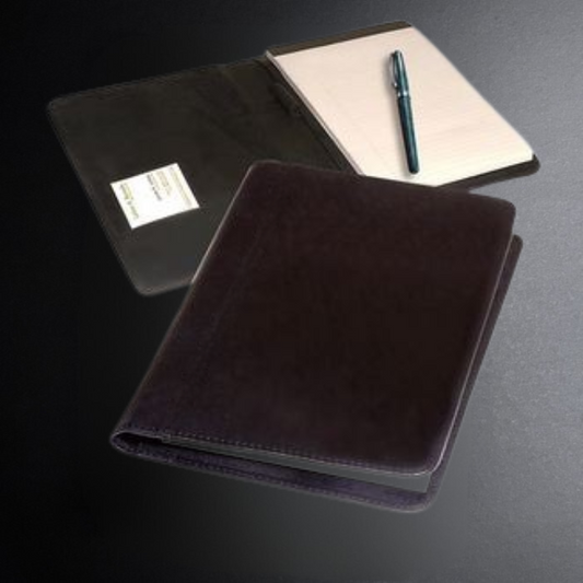 Three notebooks with a pen on a dark surface
