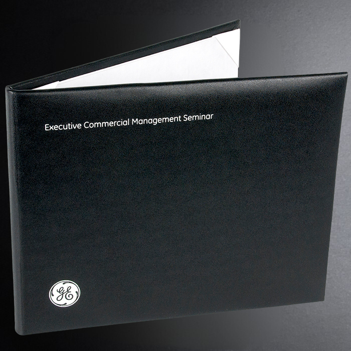 Black binder with 'Executive Commercial Management Seminar' text and GE logo on a dark background