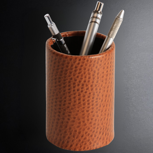 Brown leather pen holder with three pens on a dark background