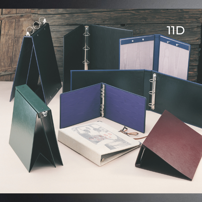 A set of folding ring binder folders shown open and closed in multiple colors, including dark green, navy, blue, burgundy, and black, arranged on a tabletop with a rustic wooden background. The text '11D' appears in the upper right.