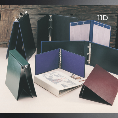 A set of folding ring binder folders shown open and closed in multiple colors, including dark green, navy, blue, burgundy, and black, arranged on a tabletop with a rustic wooden background. The text '11D' appears in the upper right.